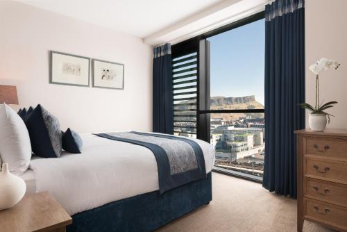 a bedroom with a bed and a large window at Princes Street Suites in Edinburgh