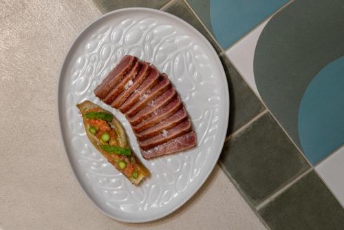 a white plate with a piece of meat and peas at Kimpton Los Monteros Marbella by IHG in Marbella