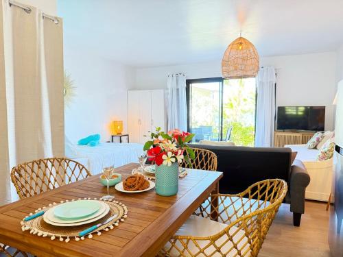 - un salon doté d'une table en bois avec des assiettes et des fleurs dans l'établissement Charming cozy beachfront studio with parking and wifi, à Bora Bora