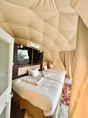 two beds in a room with a tent at Wadi Rum ZAAD luxury Camp in Disah