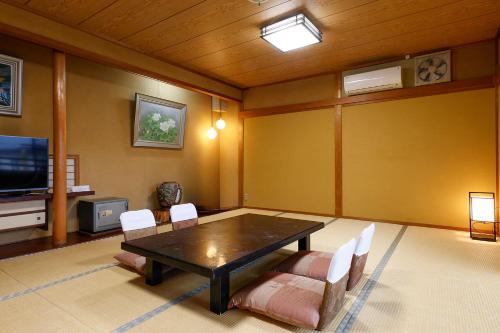a living room with a table and chairs and a tv at Yanagiso in Toyooka