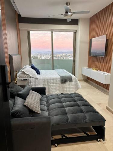 a bedroom with a bed and a couch and a large window at HOTEL TRAMONTO MAZATLAN in Mazatlán