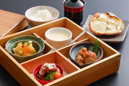 a wooden box with three bowls of food on a table at Yanagiso in Toyooka