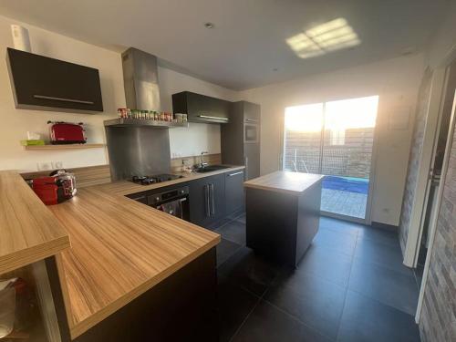 d'une cuisine équipée d'appareils en acier inoxydable et d'une grande fenêtre. dans l'établissement Charmante maison près de la mer, à Grosbreuil