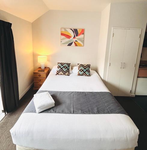 a bedroom with a large white bed with two pillows at Bush Inn Court Motel in Christchurch