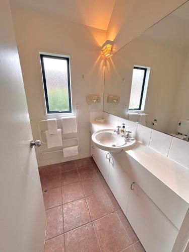 a white bathroom with a sink and a mirror at Bush Inn Court Motel in Christchurch