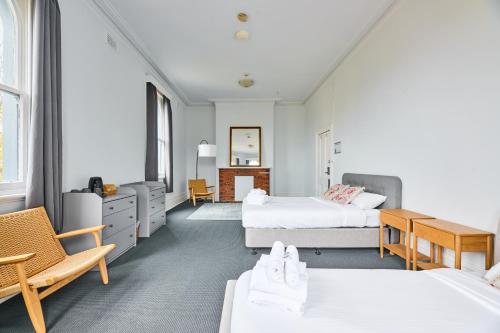 a bedroom with two beds and a desk at College Lawn Hotel in Melbourne