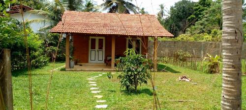 een klein huis met een rood dak op een erf bij Eco Bricks in Ahangama