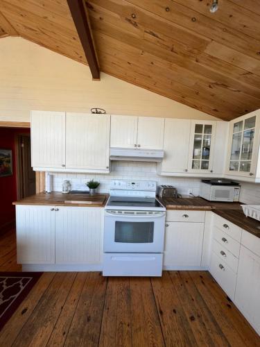 a kitchen with white cabinets and a white stove at Chalet Alpin Suisse Au Bord Du Lac in Morin Heights