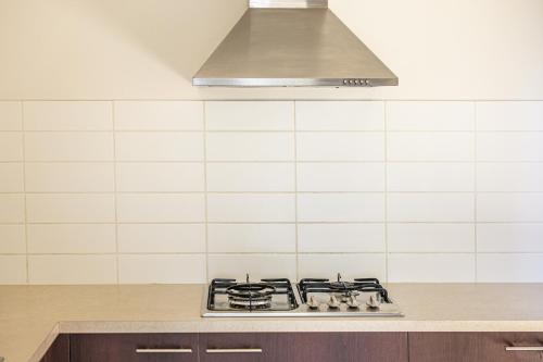 a stove top in a kitchen with a hood at StayAU 5BR Idyllic Lakefront Escape Point Cook in Point Cook