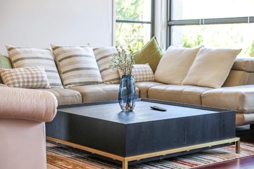 a living room with a couch and a vase on a coffee table at StayAU 5BR Idyllic Lakefront Escape Point Cook in Point Cook