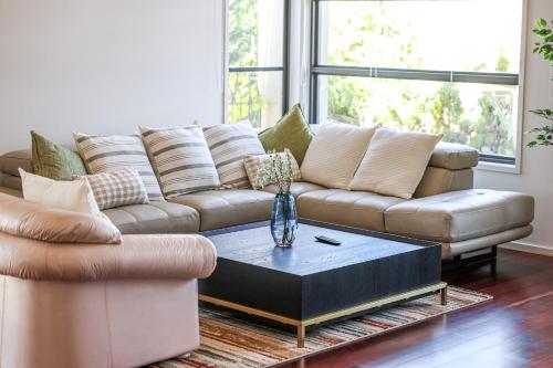 a living room with a couch and a coffee table at StayAU 5BR Idyllic Lakefront Escape Point Cook in Point Cook