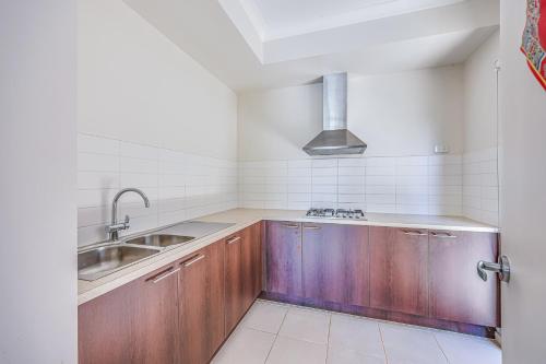 a kitchen with wooden cabinets and a sink at StayAU 5BR Idyllic Lakefront Escape Point Cook in Point Cook
