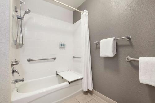 a bathroom with a tub and a shower with towels at Courtyard by Marriott San Antonio Airport in San Antonio