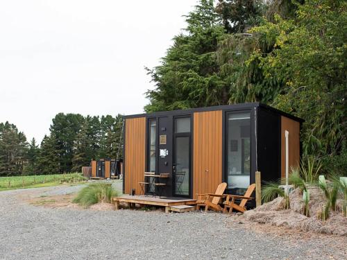 a black and orange tiny house with a table and chairs at Mackenzie Pass Retreat by Tiny Away in Burkes Pass