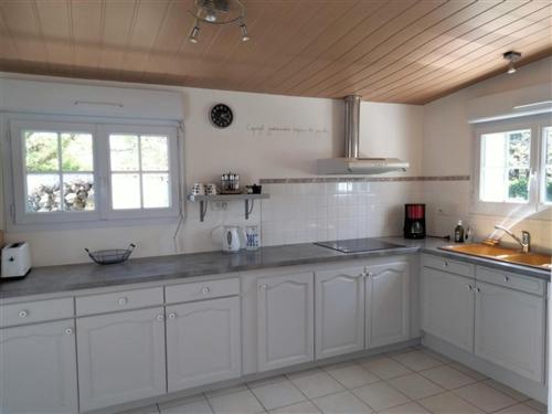 une grande cuisine blanche avec des armoires et des fenêtres blanches dans l'établissement Maison familiale avec jardin, parking privé et wifi aux Sables-d'Olonne - FR-1-331-35, à Les Sables-dʼOlonne