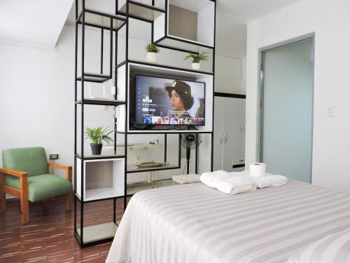 une chambre avec un lit, une télévision et une chaise dans l'établissement Estudio de Lujo, Cerca de la Plaza, à Tarija