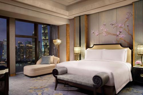 a bedroom with a bed and a chair and a window at The St. Regis on the Bund, Shanghai in Shanghai