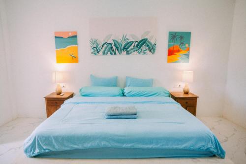 a bedroom with a blue bed with paintings on the wall at Swell Hotel, Pool Bar & Restaurant in Tanah Lot
