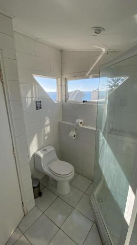 a bathroom with a toilet and a glass shower at Hostal Boutique F in El Quisco