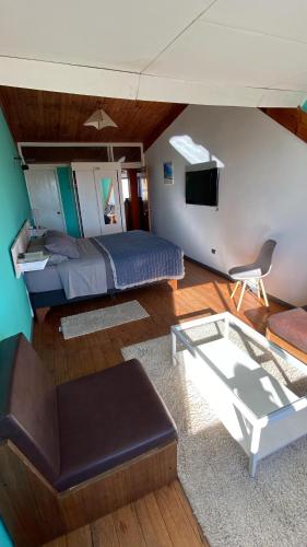 a bedroom with a bed and a couch and a table at Hostal Boutique F in El Quisco