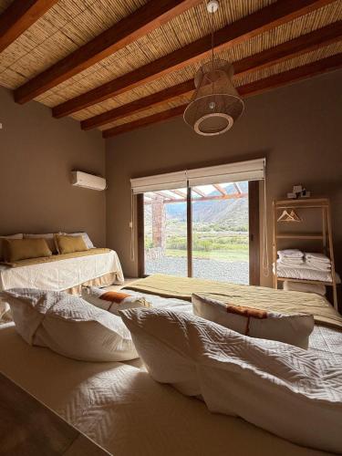 a bedroom with two beds and a large window at Distinguida Cabaña en Purmamarca in Purmamarca