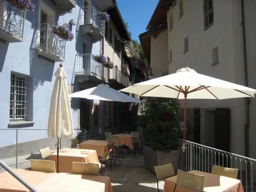 a patio with tables and umbrellas next to buildings at Hotel Ad Gallias in Bard