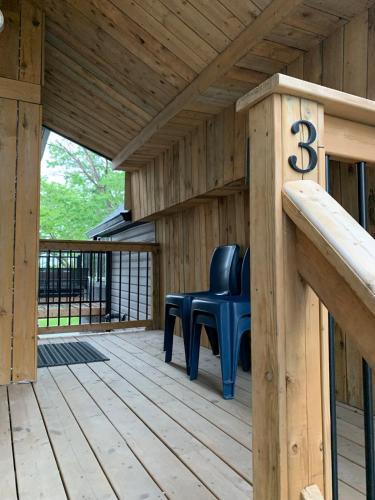 a wooden porch with two blue chairs on a deck at 2BR House - Quiet Getaway in Windsor