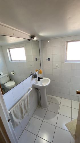 a white bathroom with a sink and a toilet at Hostal Boutique F in El Quisco