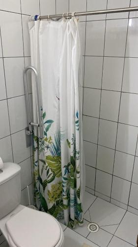 a bathroom with a shower curtain with a toilet at Hostal Boutique F in El Quisco