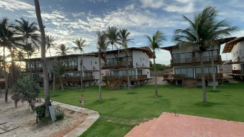 eine Person steht vor einem Gebäude mit Palmen in der Unterkunft Chalé Leão Marinho Cajueiro da Praia in Cajueiro
