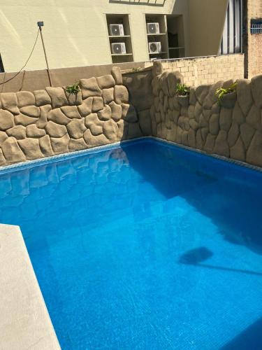 a large blue swimming pool next to a stone wall at Marbella 25 in Acapulco