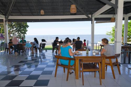 personnes assises à table dans un restaurant avec l'océan en arrière-plan dans l'établissement Oceana Dive Resort, à Gorontalo