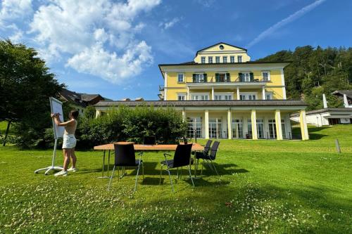 a man standing in front of a yellow house at Arabella Jagdhof Resort am Fuschlsee, a Tribute Portfolio Hotel in Hof bei Salzburg