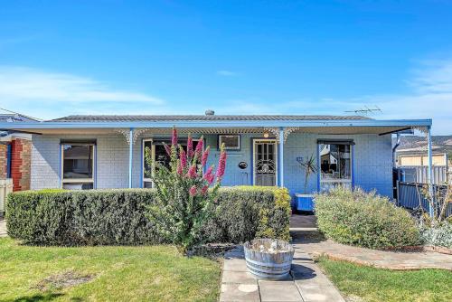 a blue house with bushes in a yard at Charming Coastal Cottage-Steps Away from the Beach in Aldinga Beach