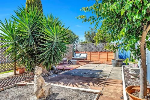 a garden with a patio with a cat statue at Charming Coastal Cottage-Steps Away from the Beach in Aldinga Beach
