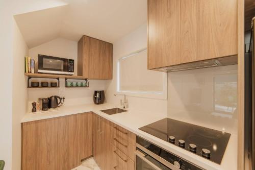 a kitchen with wooden cabinets and a microwave at Bright City Base - 1Bed Kitchen Outdoor Space in Christchurch