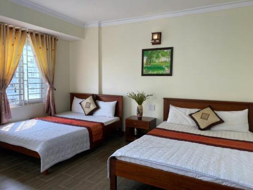 a hotel room with two beds and a window at Hoa Lư Hotel in Sầm Sơn