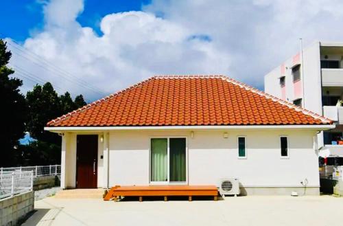 a small white house with an orange roof at 心邸 kukuru in Nakijin