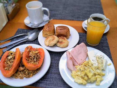 Villa Maior Hotel في ساو روكي: ثلاثة أطباق من طعام الإفطار على طاولة مع عصير البرتقال