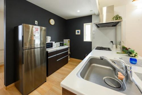 a kitchen with a stainless steel refrigerator and a sink at 心邸 kukuru in Nakijin