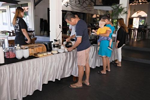 un homme tenant un bébé debout à côté d'une table dans l'établissement Oceana Dive Resort, à Gorontalo