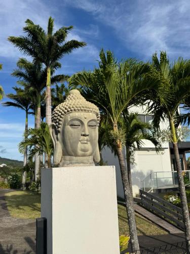 a statue of a head with palm trees in the background at Grande Villa au calme - Vue exceptionnelle - Climatisation - Piscine sel chauffée - Jardin Tropical in Vincendo