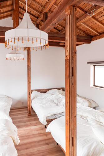 ein Schlafzimmer mit drei Betten und einem Kronleuchter in der Unterkunft Kumano Kodo Private House-CHILL HOUSE-Nachikatsuura in Nachikatsuura
