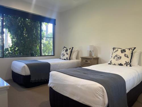 two beds in a room with a window at The Noosa Apartments in Noosa Heads