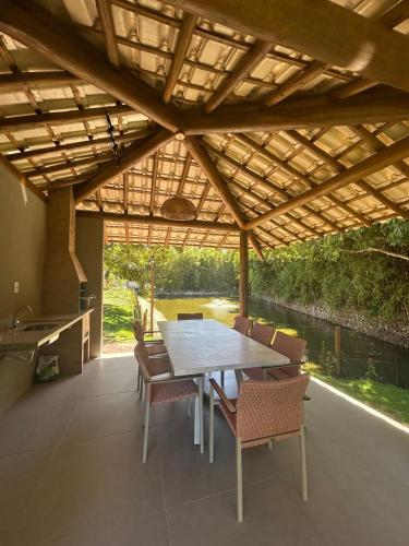 a patio with a table and chairs under a roof at Bioflora Residence Itacimirim in Camacari