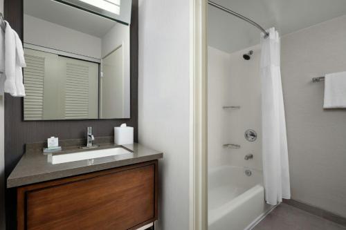 a bathroom with a sink and a shower with a mirror at Courtyard by Marriott Stockton in Stockton