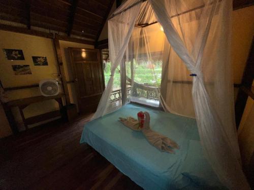 a bed with a drape with a toy animal on it at Alby Lodge Cahuita in Cahuita