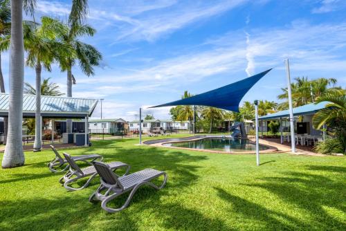 a group of chaise lounges on the grass near a pool at Townsville Lakes Holiday Park in Townsville