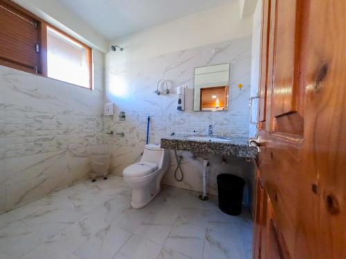 a white bathroom with a toilet and a sink at Cascade Mountain Retreat Manali in Manāli